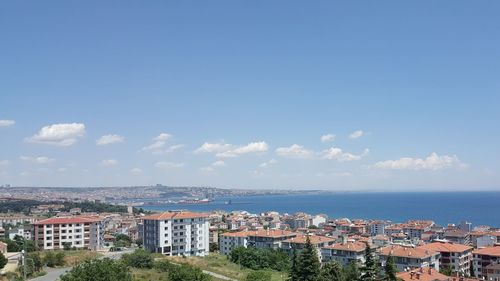 Aerial view of townscape by sea against sky