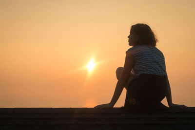 Rear view of man sitting at sunset