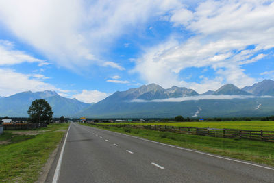 Empty road leading towards mountains against sky