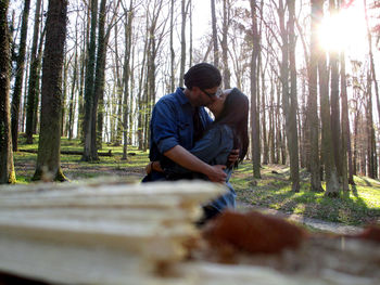 Couple kissing against trees in forest