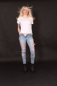 Portrait of smiling young woman standing against gray background