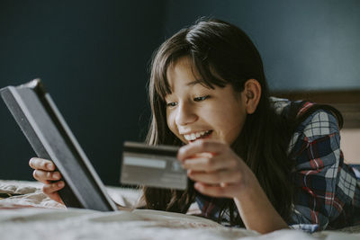 Portrait of girl holding a credit card and making online purchases on a ipad 