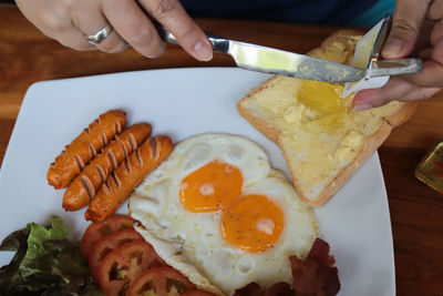 Close-up of hand holding  knife and jam