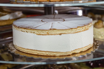 Big cheesecake inside a pastry display stand.
