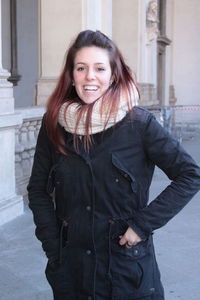 Smiling young woman wearing warm clothing in city during winter