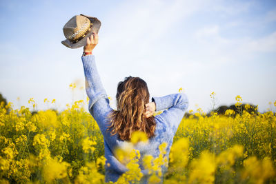 Full length of woman with yellow flowers on field