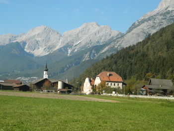 Houses on field by mountains against sky