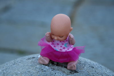 Close-up of cute doll on rock outdoors