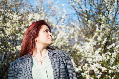 Young woman standing against trees