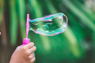 Close-up of hand making bubbles with wand