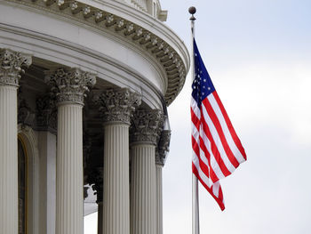 Low angle view of flags against sky next to the us capitol building in washington dc.