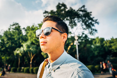 Portrait of young man wearing sunglasses against trees