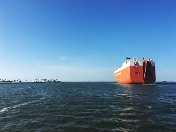 Ship sailing on sea against clear blue sky