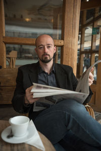 Portrait of businessman reading newspaper at cafe