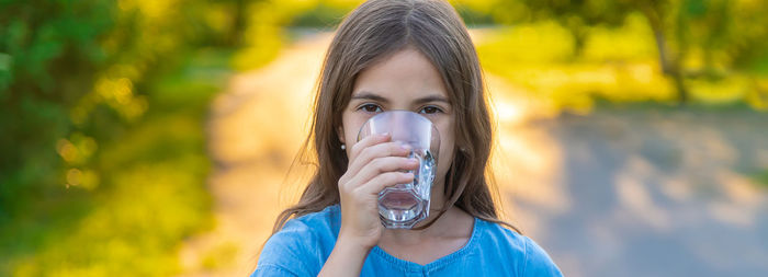 Portrait of girl drinking water at park