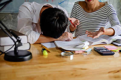 Friends studying with school supplies on table at home