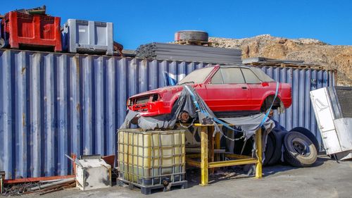 Stack of old car on land against clear blue sky