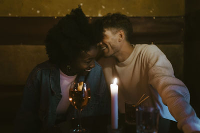 Happy multiracial couple having fun during candlelight date at bar