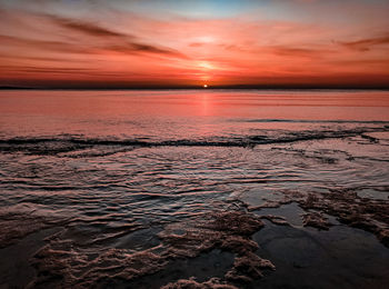 Scenic view of sea against dramatic sky during sunset