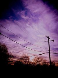 Low angle view of electricity pylon against cloudy sky