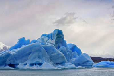 Scenic view of snow covered landscape against sky. an iceberg float in water.