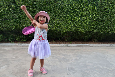 Full length of a smiling girl standing against plants