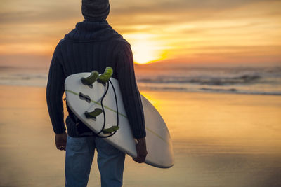 Man standing on beach against sky during sunset