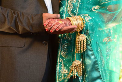 Midsection of groom holding bride hand during wedding ceremony