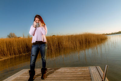 Woman standing by lake against sky