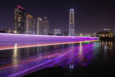 Illuminated buildings in city against sky at night