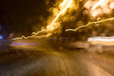 Light trails on street against sky at night