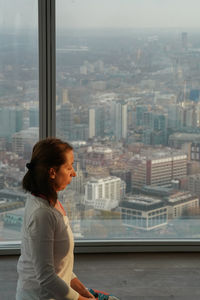 Young woman standing by river against cityscape