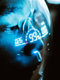 Close-up of a young man wearing a face shield with digital readout in a darkroom