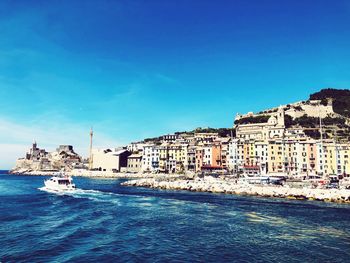 View of buildings by sea against blue sky