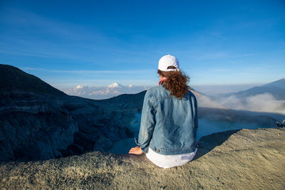 Rear view of woman standing on mountain against sky