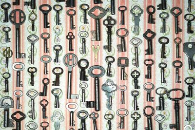Full frame shot of various antique keys hanging on patterned wall