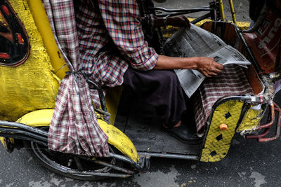 Low section of man holding newspaper while sitting in vehicle