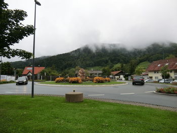 Vehicles on road by mountain against sky