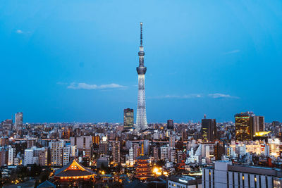 Illuminated buildings in city against sky