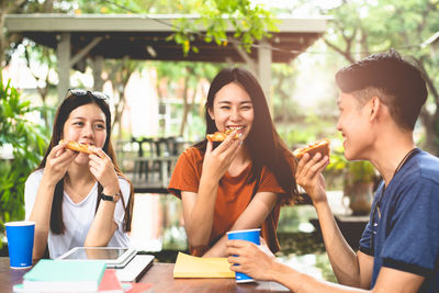 Young woman eating food on table at restaurant
