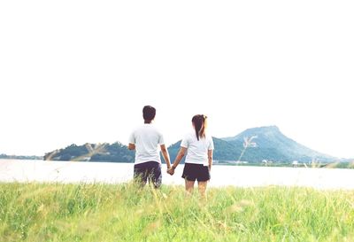 Rear view of couple walking on grass