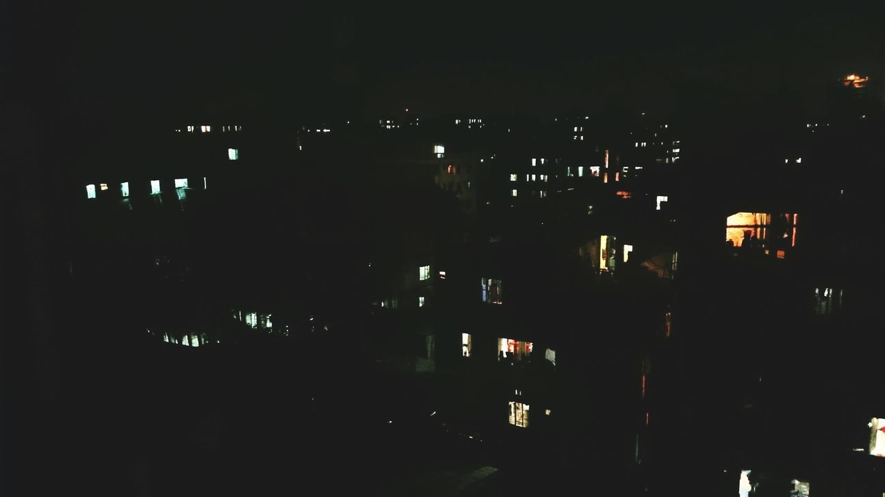 SILHOUETTE BUILDINGS AGAINST ILLUMINATED CITY AT NIGHT