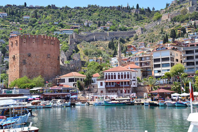 Sailboats moored on river by buildings in city