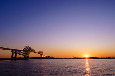 Bridge over river against clear sky during sunset