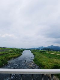 River amidst green landscape against sky