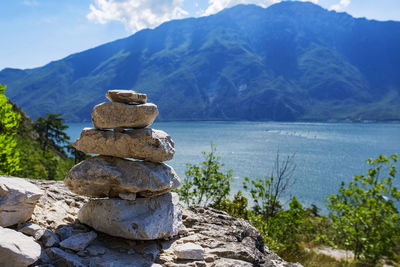 Stack of stones by lake against sky