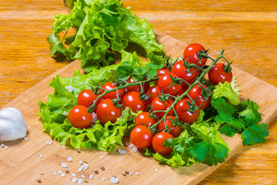 Fresh cherry tomatoes with green salad and garlic on a cutting board. healthy food concept. 