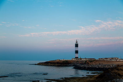 Lighthouse by sea against sky