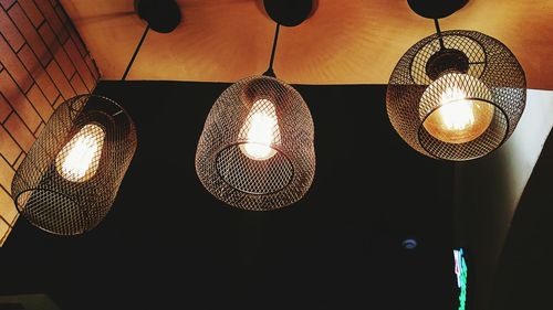 Low angle view of illuminated light bulb hanging from ceiling
