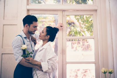 Romantic couple standing by closed door at home